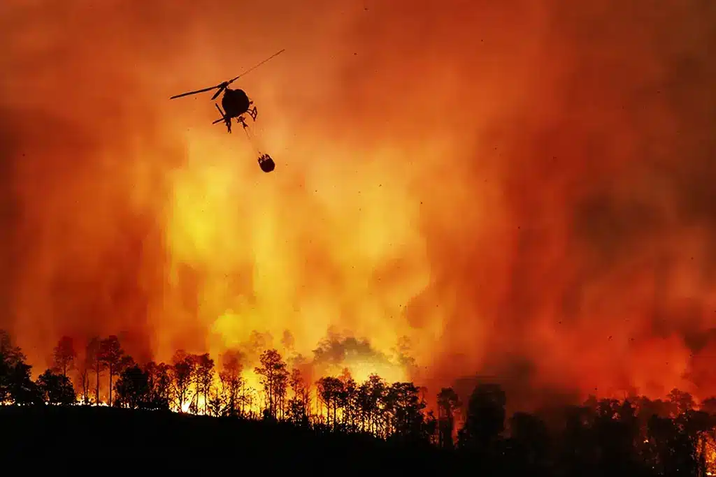 Helicopter fighting wildfire with water bucket